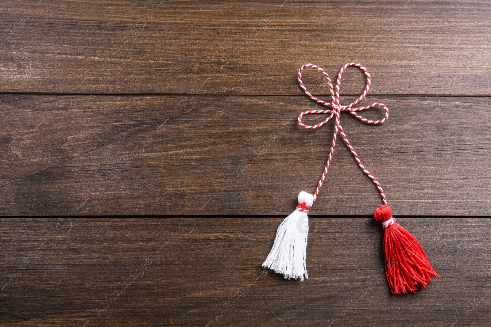 Photo of Traditional martisor on wooden background, top view with space for text. Beginning of spring celebration