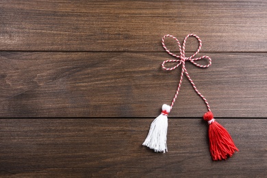 Traditional martisor on wooden background, top view with space for text. Beginning of spring celebration