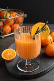 Photo of Delicious tangerine liqueur in glass and fresh fruits on grey table, closeup