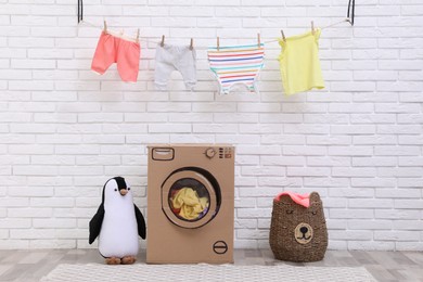 Photo of Toy cardboard washing machine and laundry indoors
