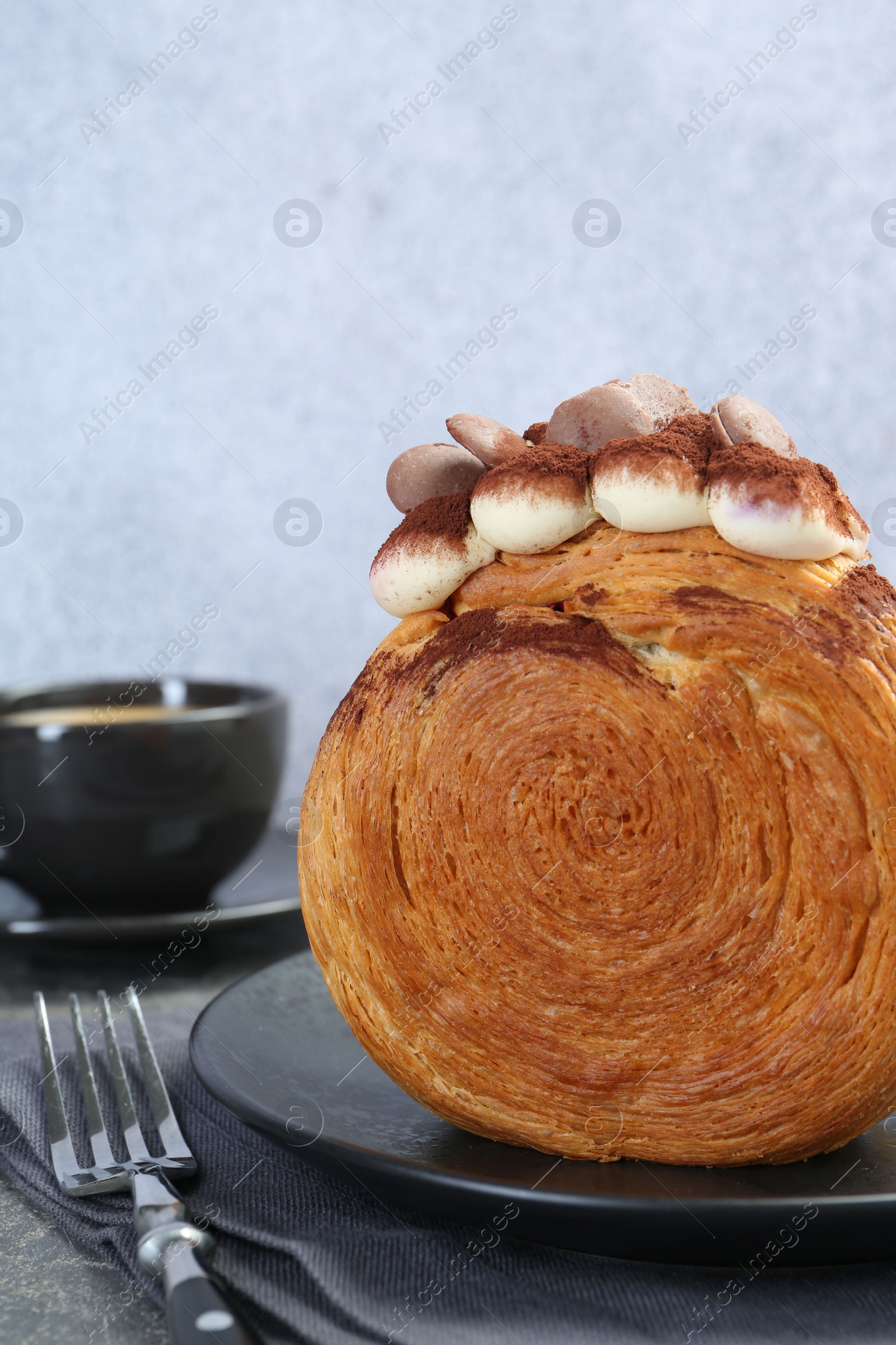 Photo of Round croissant with chocolate chips and cream served on table, closeup. Tasty puff pastry