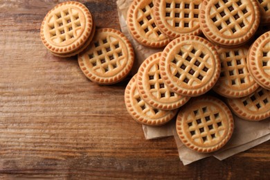 Photo of Tasty sandwich cookies with cream on wooden table, flat lay. Space for text