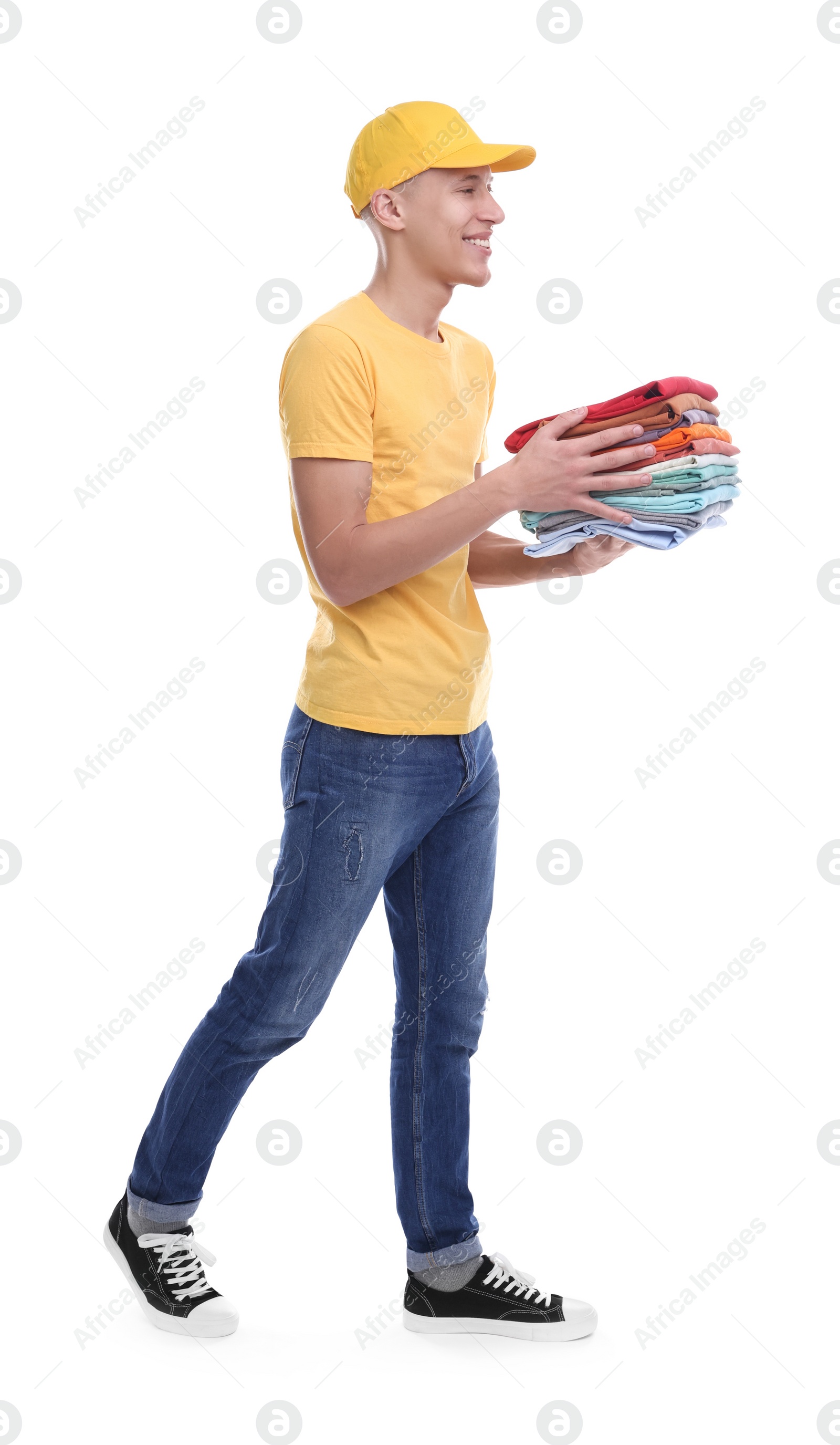 Photo of Dry-cleaning delivery. Happy courier holding folded clothes on white background