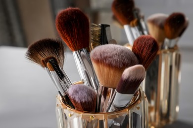 Photo of Set of professional makeup brushes near mirror, closeup