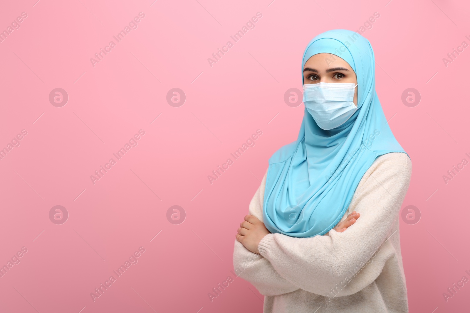 Photo of Portrait of Muslim woman in hijab and medical mask on pink background, space for text