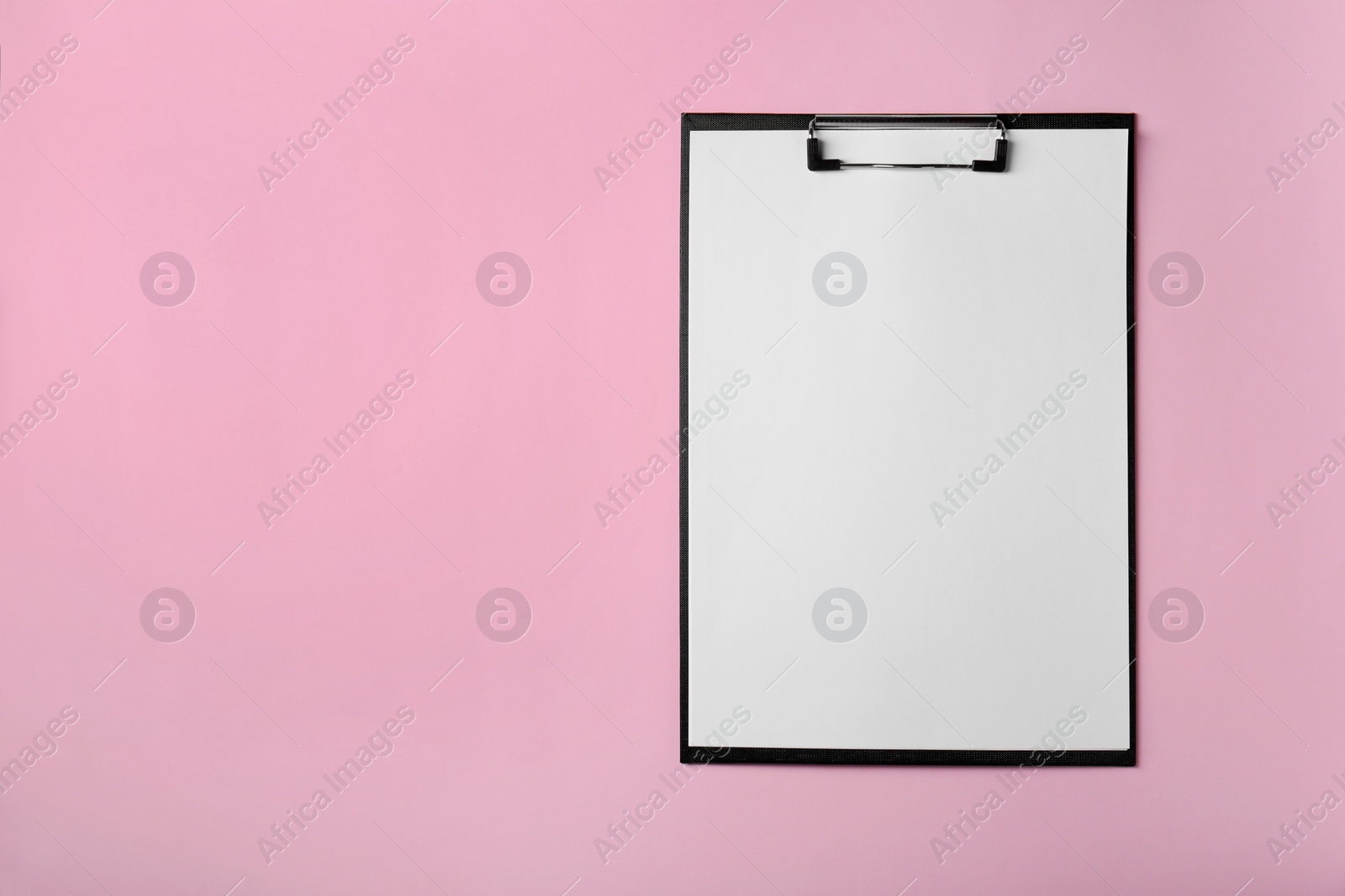 Photo of Black clipboard with sheet of blank paper on pink background, top view. Space for text