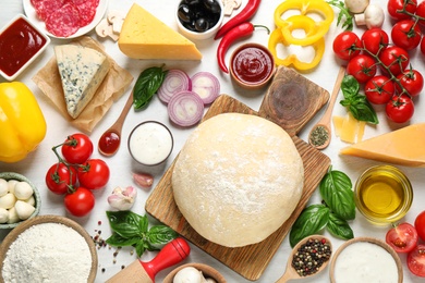 Photo of Flat lay composition with dough and fresh ingredients for pizza on white wooden table