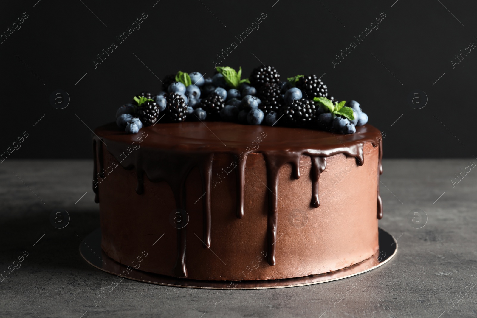 Photo of Fresh delicious homemade chocolate cake with berries on table against dark background