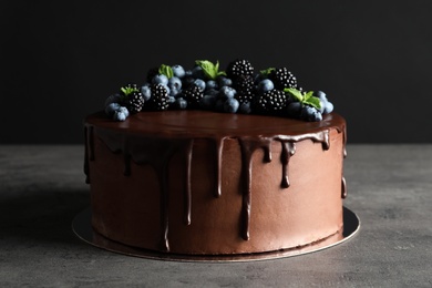 Photo of Fresh delicious homemade chocolate cake with berries on table against dark background