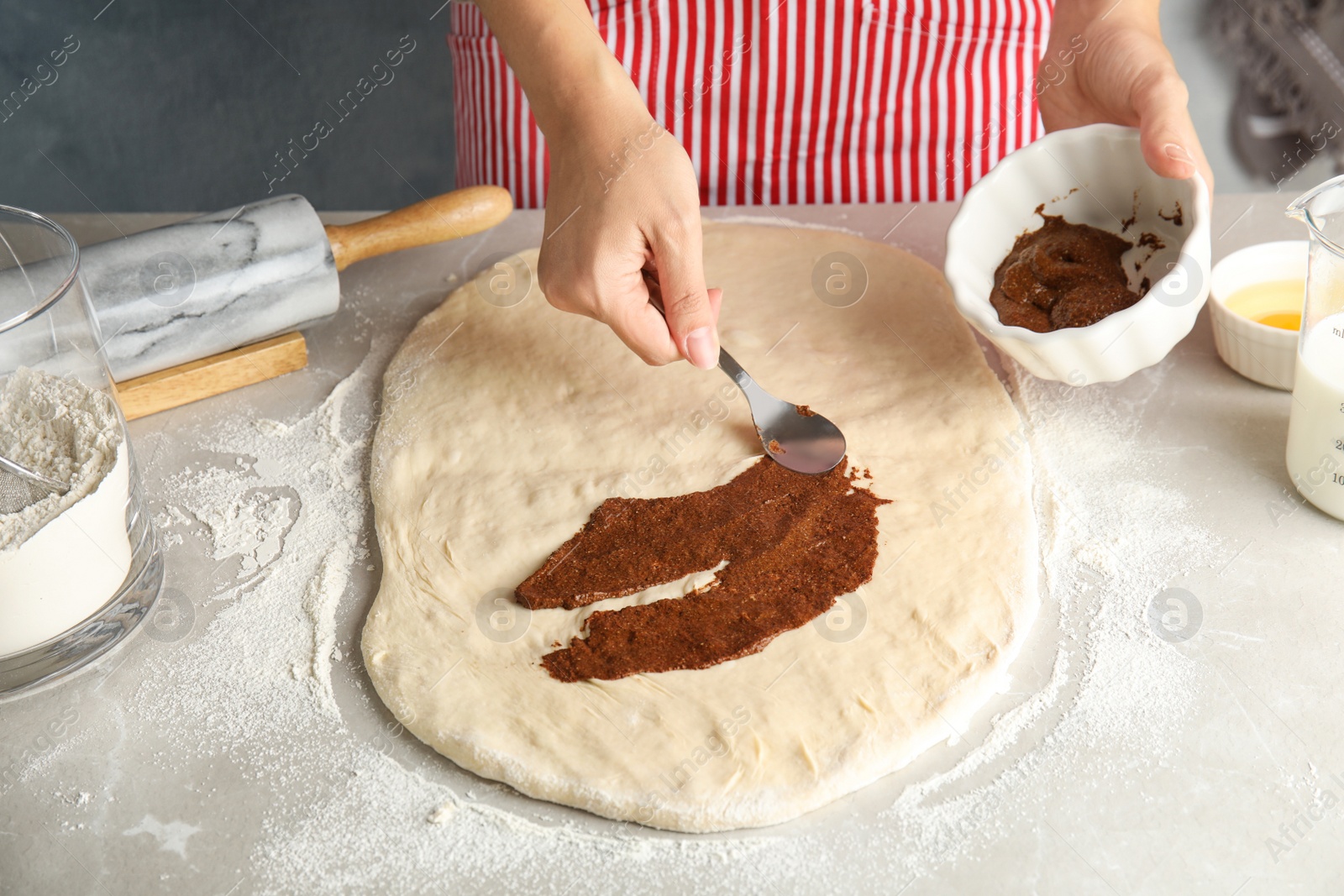 Photo of Woman making cinnamon rolls at table, closeup