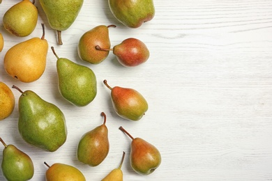 Ripe pears on white wooden background, top view. Space for text