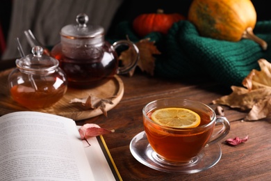 Photo of Cup of hot drink and book on wooden table. Cozy autumn atmosphere