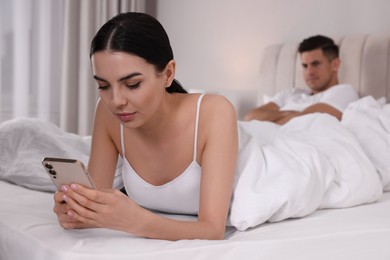 Internet addiction. Woman with smartphone ignoring her boyfriend in bedroom