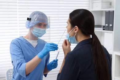 Laboratory testing. Doctor in uniform taking sample from patient's nose with cotton swab at hospital