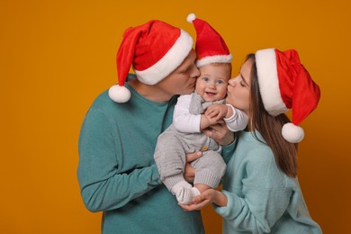 Photo of Happy couple with cute baby wearing Santa hats on yellow background. Christmas season