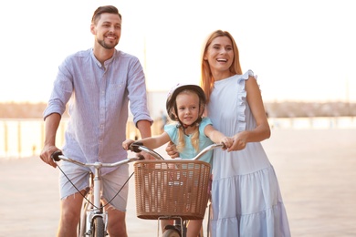 Photo of Happy family riding bicycles outdoors on summer day