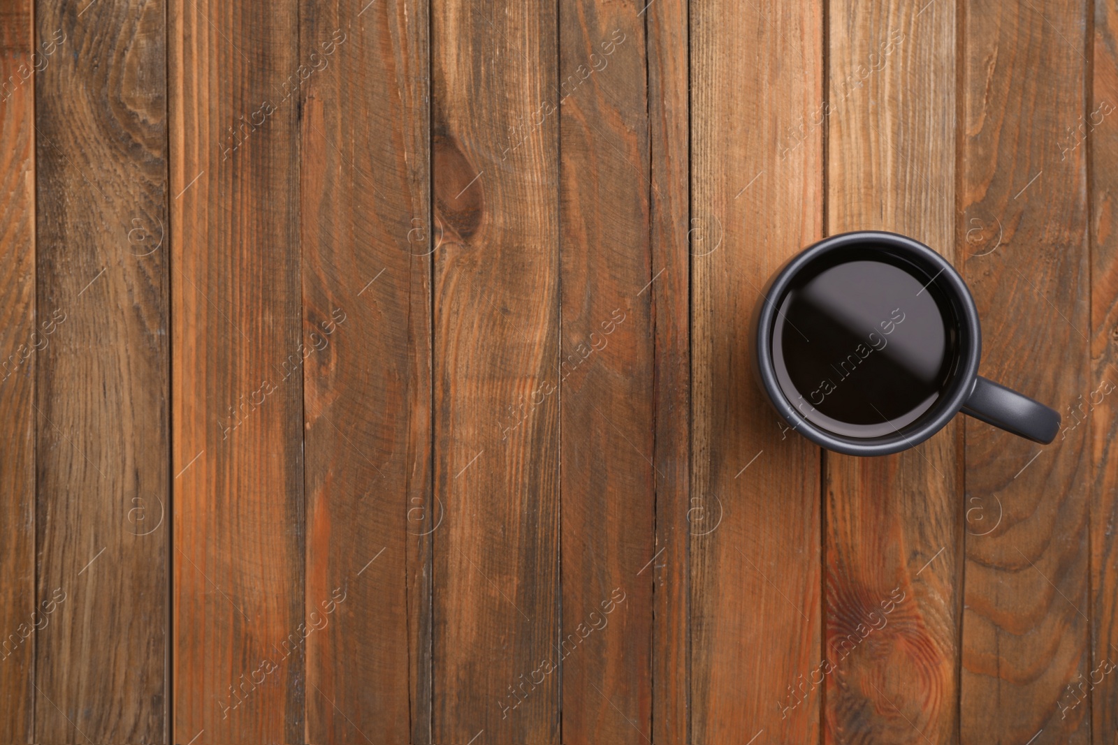 Photo of Ceramic cup with hot aromatic coffee on wooden background, top view