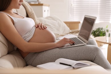 Photo of Pregnant woman working on sofa at home, closeup. Maternity leave