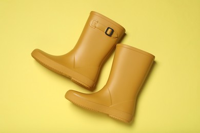 Photo of Yellow rubber boots on color background, flat lay