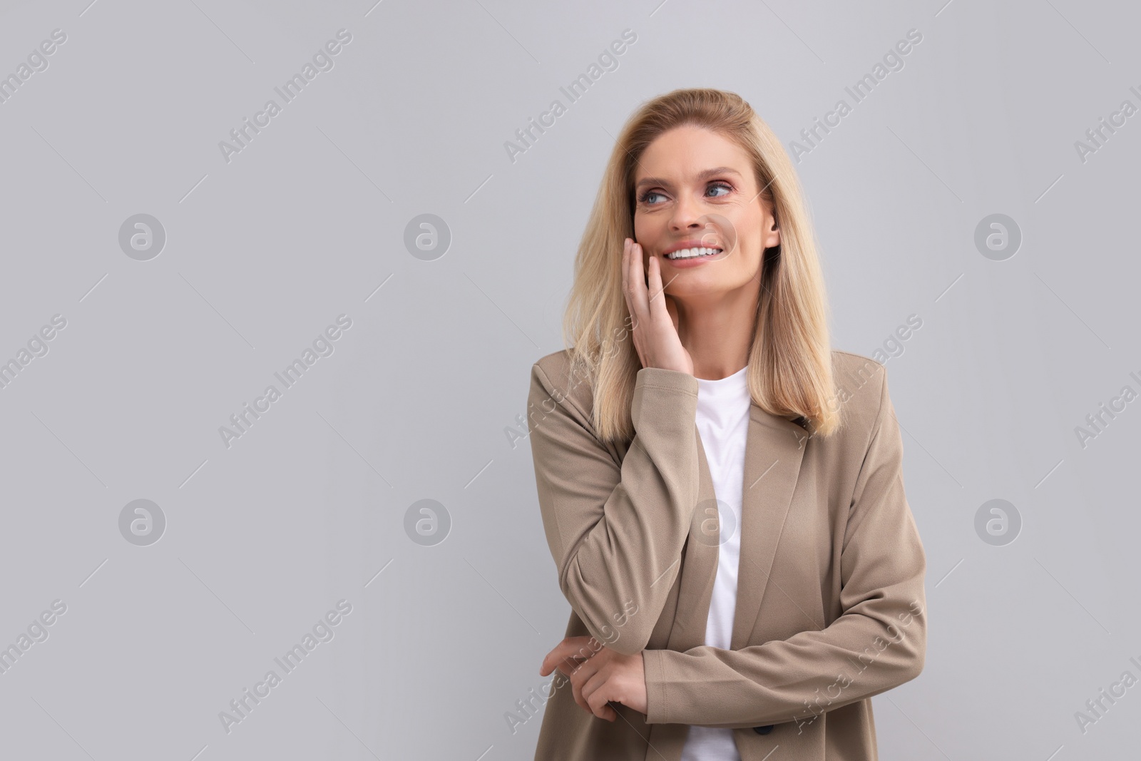 Photo of Portrait of smiling middle aged businesswoman on light grey background. Space for text