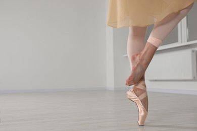Ballerina in pointe shoe dancing indoors, closeup. Space for text