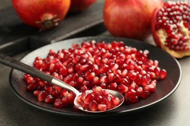 Photo of Ripe juicy pomegranate grains on grey table