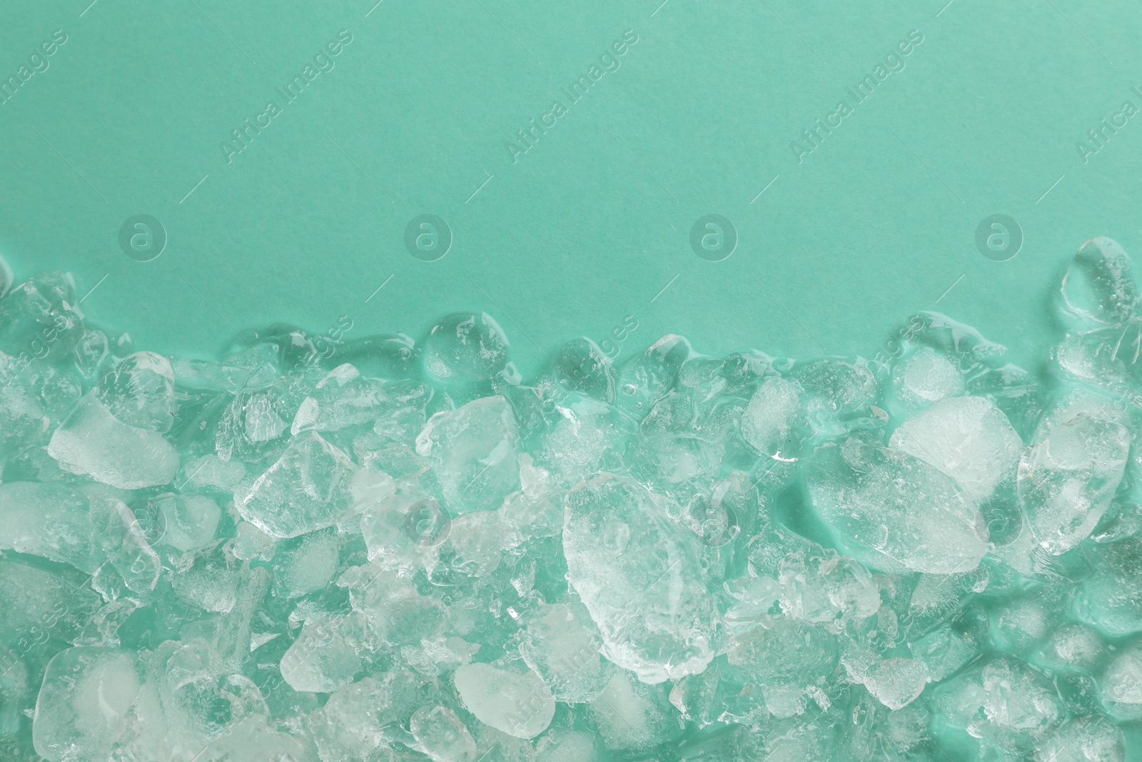 Photo of Pile of crushed ice on turquoise background, top view. Space for text