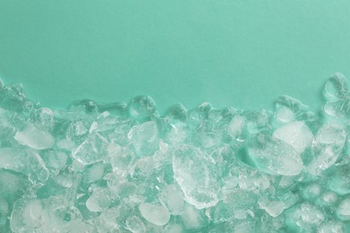 Photo of Pile of crushed ice on turquoise background, top view. Space for text