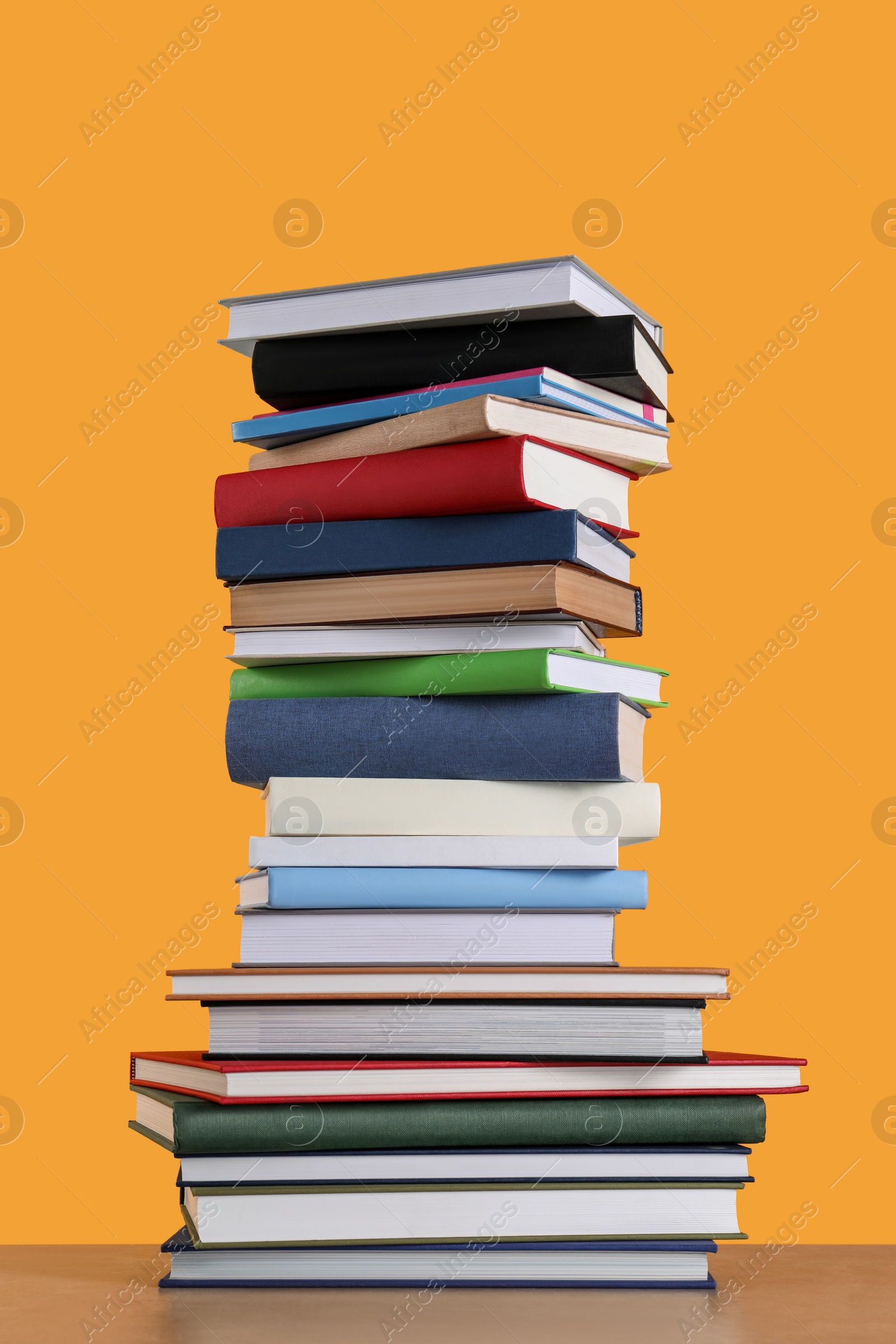 Photo of Stack of hardcover books on orange background