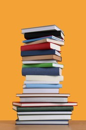 Photo of Stack of hardcover books on orange background