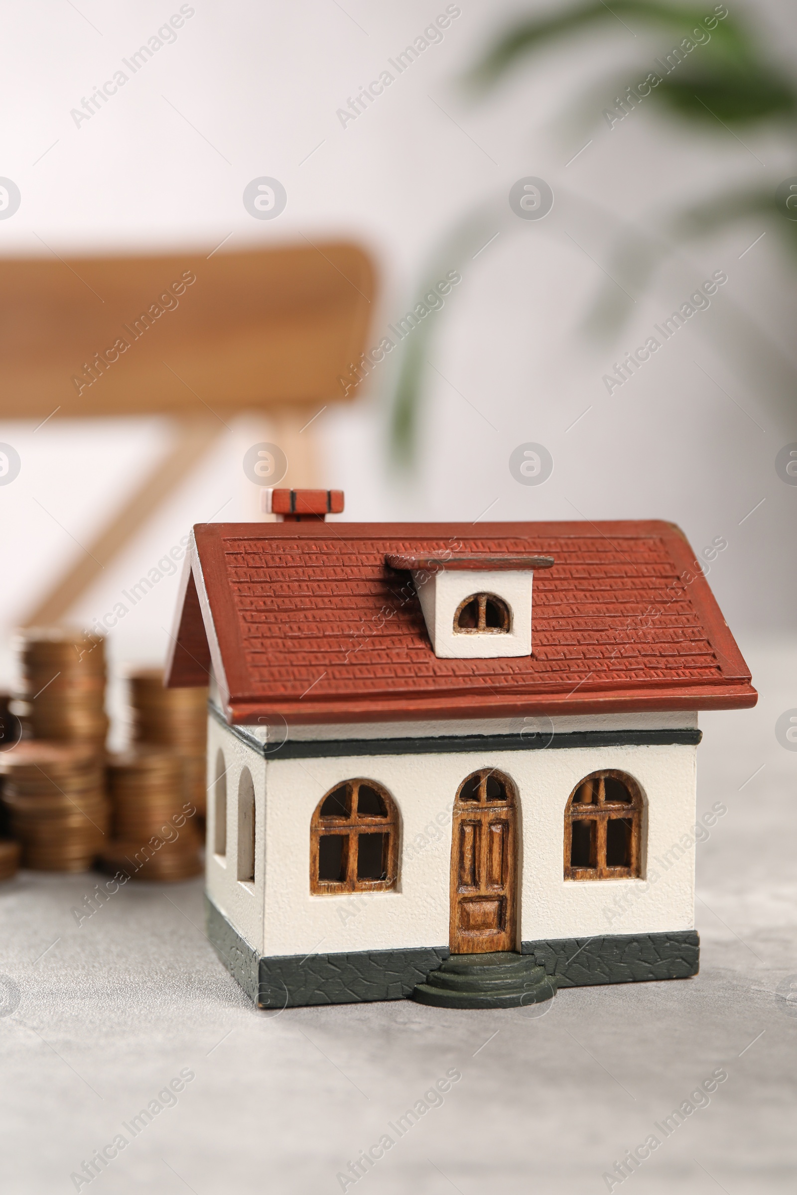 Photo of House model and stacked coins on grey table indoors, selective focus