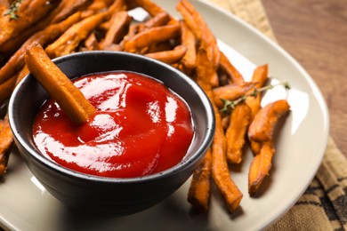 Photo of Sweet tasty potato fries and ketchup on plate, closeup