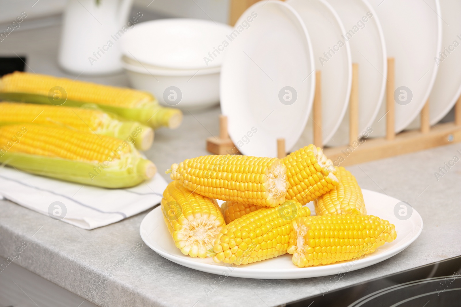 Photo of Plate with ripe corn cobs on kitchen table