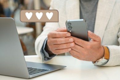 Image of Long distance love. Man sending or receiving text message at table, closeup. Speech bubble with hearts near device