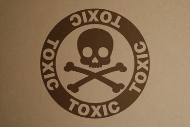 Image of Hazard warning sign (skull-and-crossbones symbol and word TOXIC) on kraft paper, top view