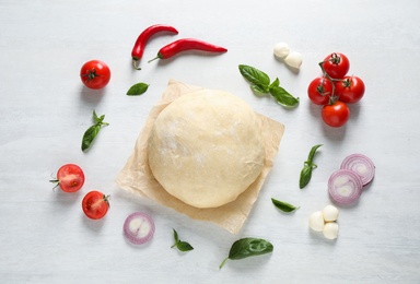 Photo of Flat lay composition with dough and fresh ingredients for pizza on white wooden table