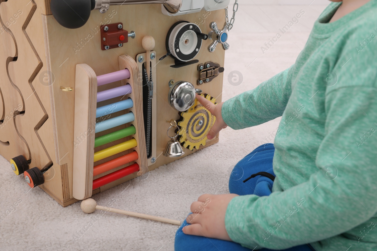 Photo of Little child playing with busy board cube on floor, closeup