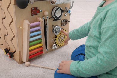 Little child playing with busy board cube on floor, closeup