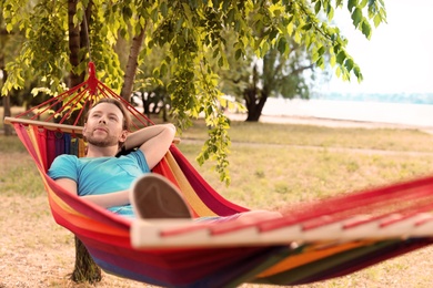 Photo of Handsome young man resting in hammock outdoors