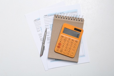 Calculator, documents and stationery on white table, flat lay. Tax accounting