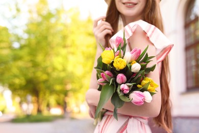 Photo of Teenage girl with bouquet of tulips on city street, closeup. Space for text