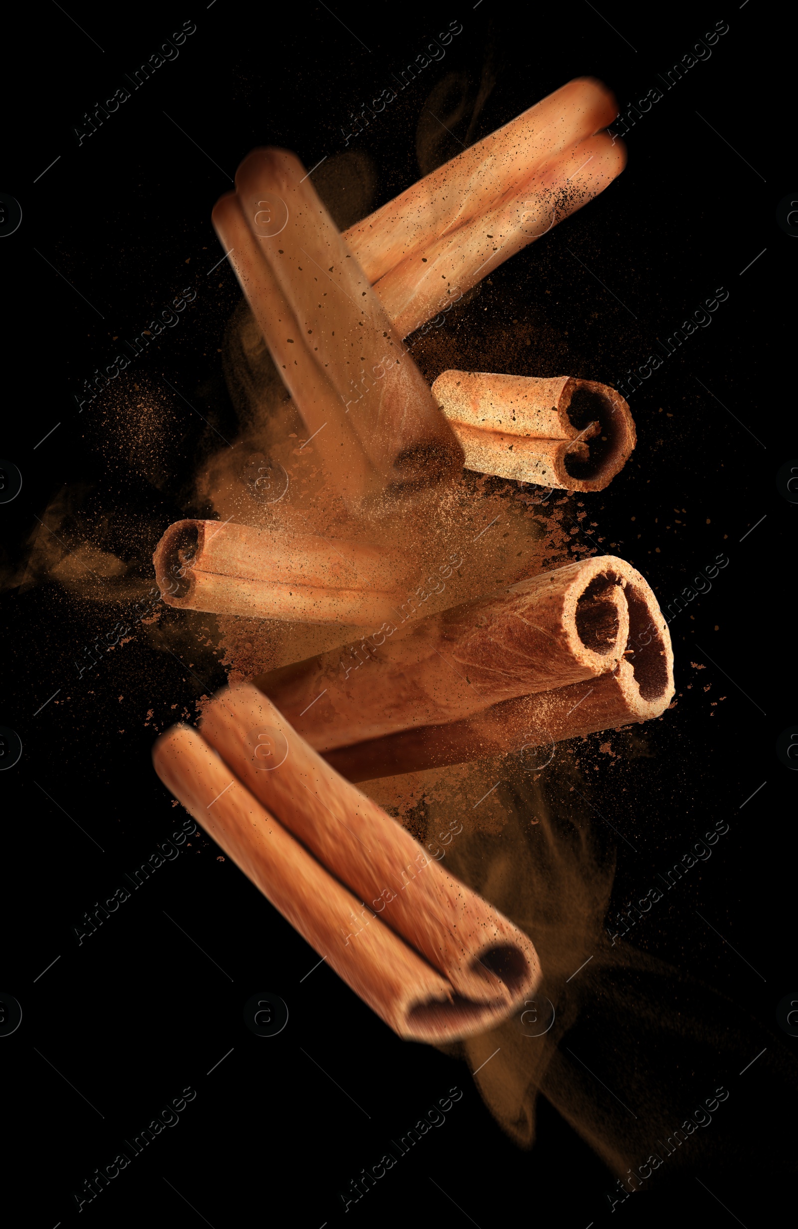 Image of Aromatic cinnamon sticks and powder flying on black background