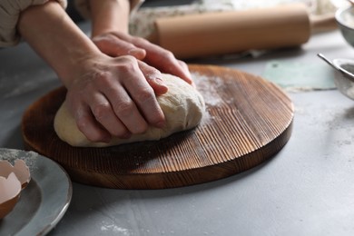 Woman kneading dough at grey table, closeup