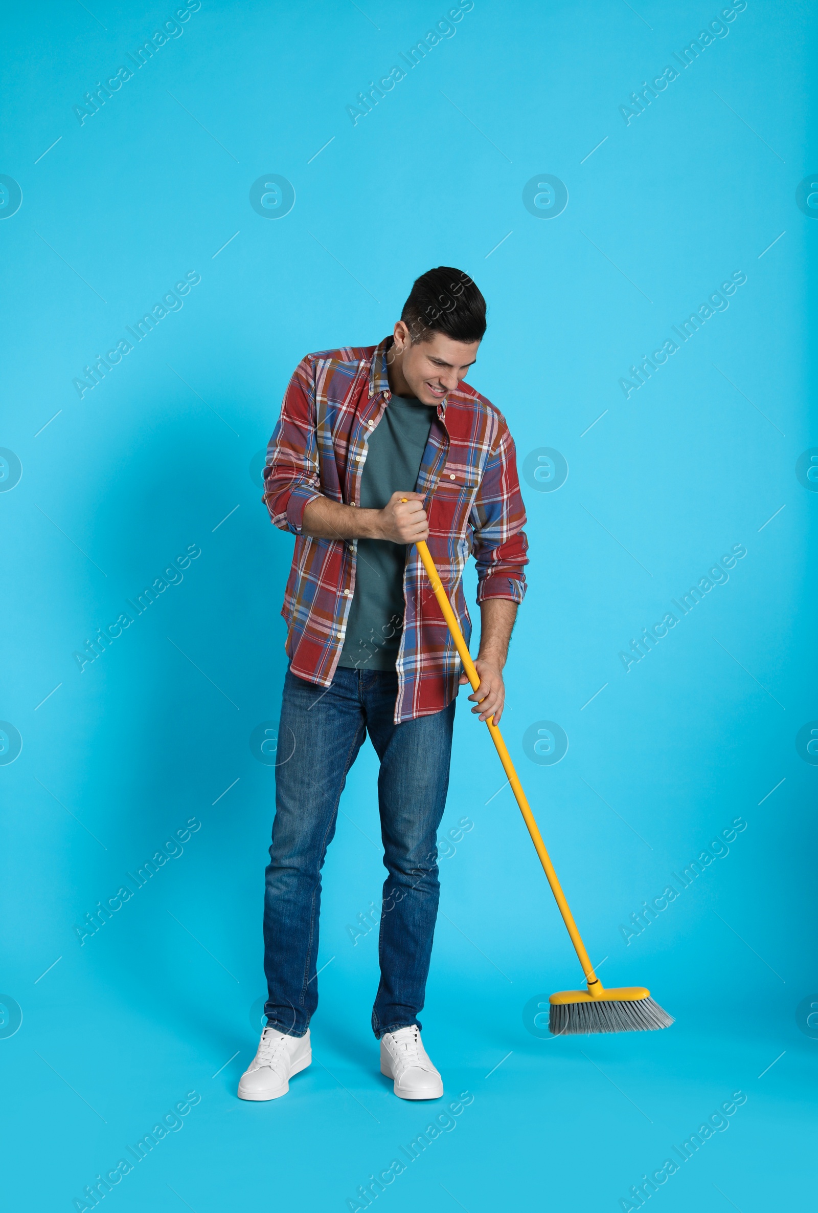 Photo of Man with yellow broom on light blue background