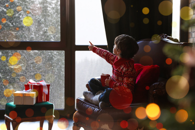 Photo of Little boy waiting for Santa Claus near window indoors. Christmas holiday