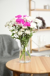 Photo of Beautiful bouquet of Chrysanthemum flowers on wooden table indoors. Interior design