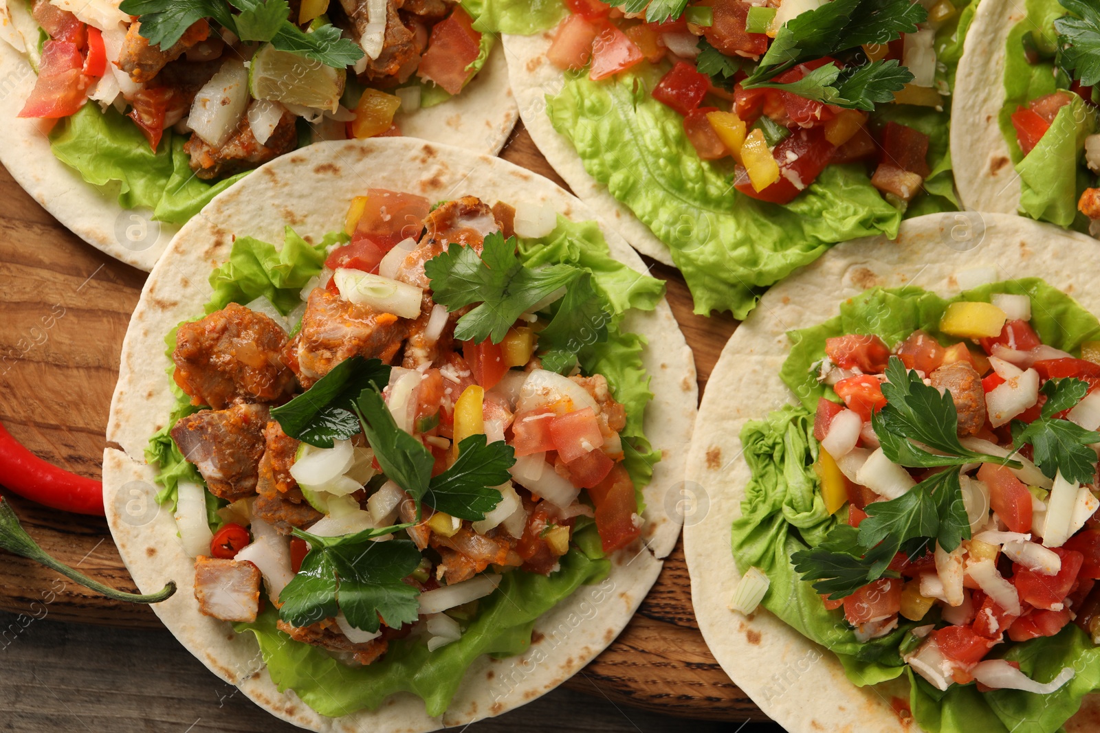 Photo of Delicious tacos with vegetables and meat on wooden table, flat lay