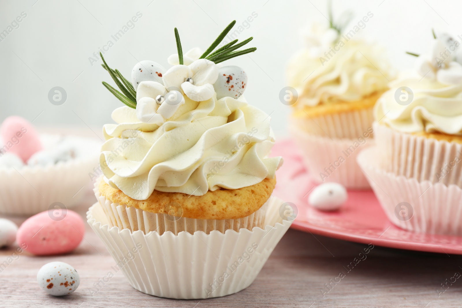 Photo of Tasty Easter cupcakes with vanilla cream on wooden table