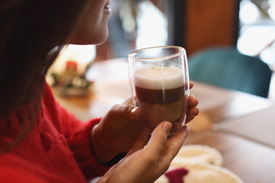 Woman with fresh morning coffee at table in cafe, closeup