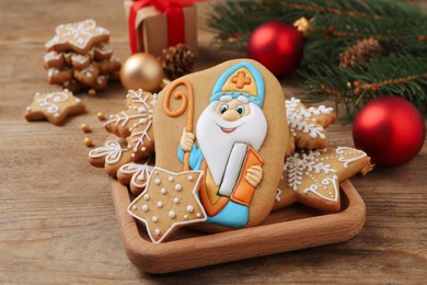 Photo of Tasty gingerbread cookies and festive decor on wooden table. St. Nicholas Day celebration